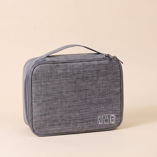 Stowmade tech organiser closed, grey heather fabric with carry handle, on a warm sand background #Gray