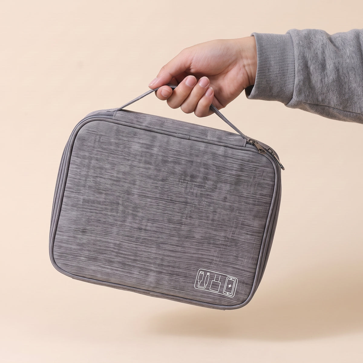 Stowmade tech organiser in grey held by its carry handle in one hand, showing how compact it is #Gray
